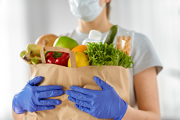 Image showing woman in gloves with food in paper bag at home