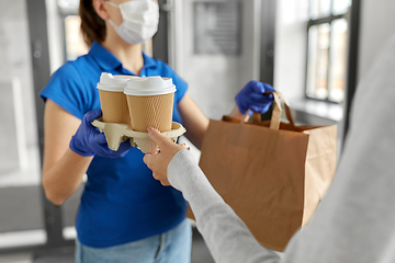 Image showing delivery girl in mask giving paper bag to woman