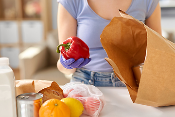 Image showing woman in gloves taking food from paper bag at home