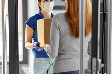 Image showing delivery girl in face mask giving parcel to woman