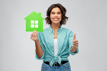 Image showing smiling woman with green house showing thumbs up