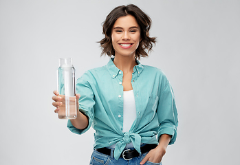 Image showing smiling young woman holding water in glass bottle