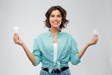 Image showing smiling woman comparing different light bulbs