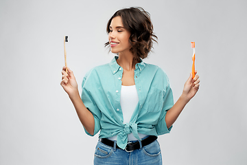 Image showing woman comparing wooden and plastic toothbrush