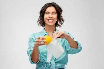 Image showing happy woman putting orange into reusable bag