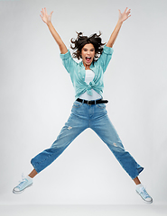 Image showing happy young woman jumping over grey background