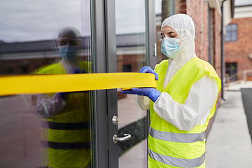 Image showing healthcare worker sealing door with caution tape