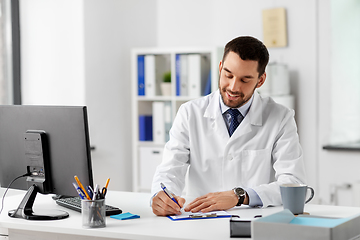 Image showing smiling male doctor with clipboard at hospital