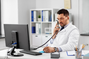 Image showing male doctor calling on desk phone at hospital
