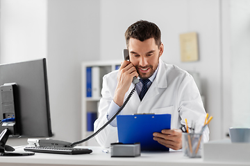 Image showing male doctor calling on desk phone at hospital