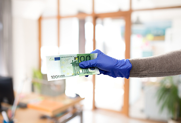 Image showing close up of hand in medical glove with money