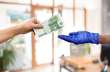 Image showing close up of hand in medical glove giving money