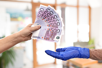 Image showing close up of hand in medical glove giving money