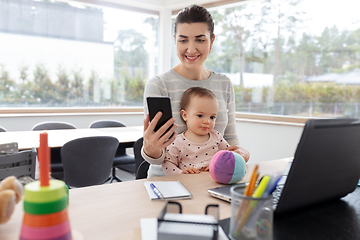 Image showing mother with baby and phone working at home office