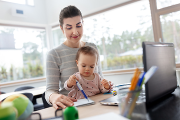 Image showing mother with baby working at home office