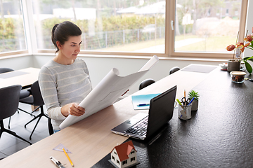 Image showing young woman with blueprint working at home office