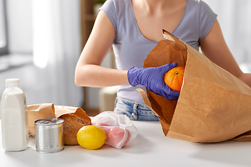 Image showing woman in gloves taking food from paper bag at home