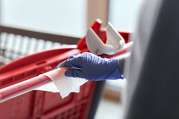 Image showing hand cleaning shopping cart handle with wet wipe