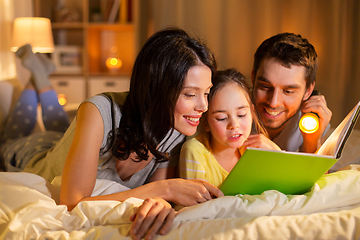 Image showing happy family reading book in bed at night at home