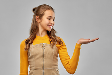 Image showing happy teenage girl holding something on empty hand