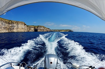 Image showing Fisheye view of the powerboat stern trail on sea water and the cliffs of Gozo island in Malta in bright day