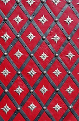 Image showing Medieval red door with diagonal iron stripes and silver stars