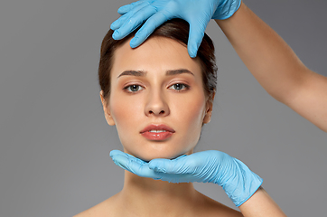 Image showing beautiful young woman face and hand in gloves