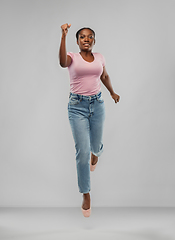 Image showing happy african american woman jumping over grey