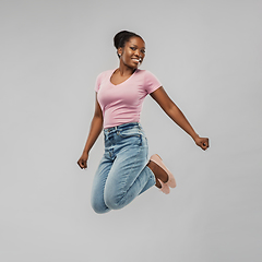 Image showing happy african american woman jumping over grey