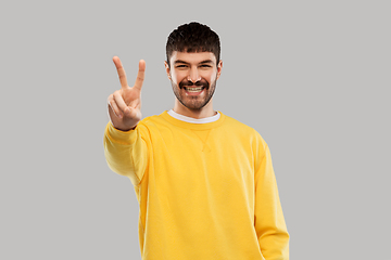 Image showing young man showing peace over grey background