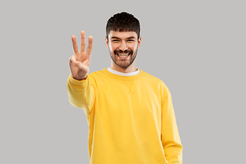 Image showing man in yellow sweatshirt showing three fingers