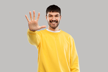 Image showing smiling young man showing his hand or five fingers