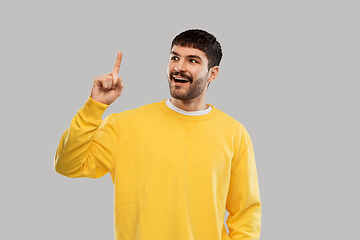 Image showing young man showing one finger in yellow sweatshirt