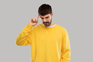 Image showing thinking young man in yellow sweatshirt