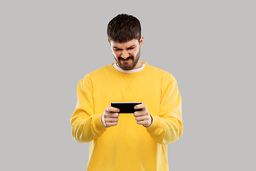 Image showing displeased young man with smartphone