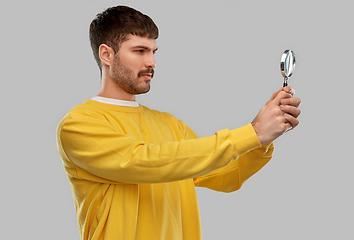 Image showing man in yellow sweatshirt with magnifier