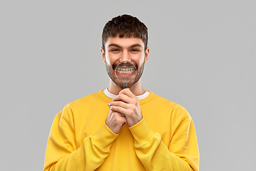 Image showing smiling man with magnifier showing his teeth