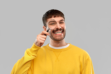 Image showing smiling man in yellow sweatshirt with magnifier