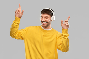 Image showing happy smiling young man in headphones dancing