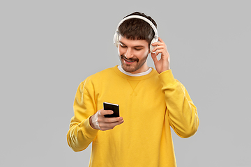 Image showing smiling young man with headphones and smartphone