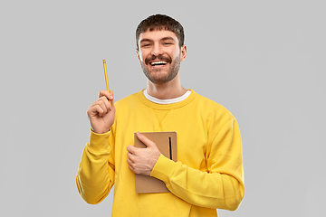 Image showing happy man in yellow sweater with diary and pencil