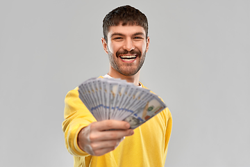 Image showing smiling young man in yellow sweatshirt with money