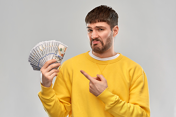 Image showing displeased man in sweatshirt with dollar money