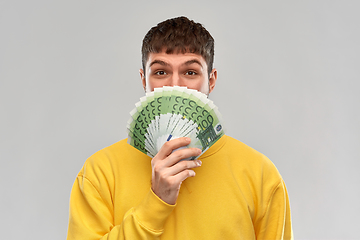 Image showing happy young man in yellow sweatshirt with money