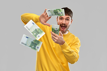 Image showing happy man in yellow sweatshirt pouring money
