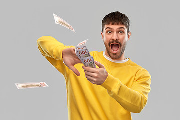 Image showing happy man in yellow sweatshirt throwing money