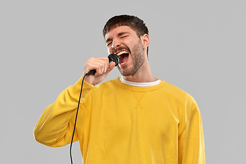 Image showing man in yellow sweatshirt with microphone singing