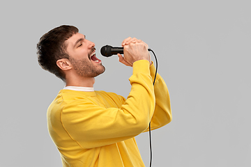 Image showing man in yellow sweatshirt with microphone singing