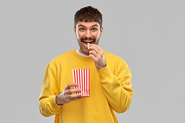 Image showing smiling man in yellow sweatshirt eating popcorn