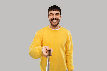 Image showing happy young man taking picture with selfie stick